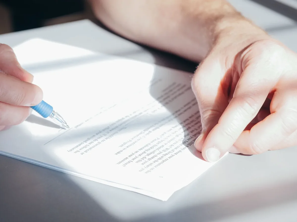 Stock photo: Hand signing a document in sunlight on a light desk